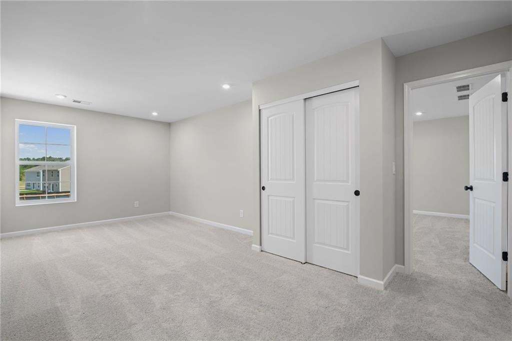 Expansive carpeted room featuring a window, recessed lighting, and a bi-fold closet with panel doors