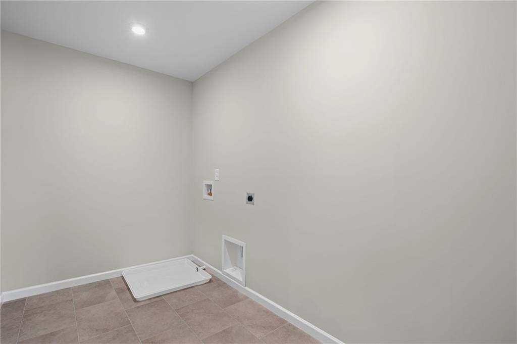 Recessed ceiling light, white painted walls, tile flooring, and utility hookups