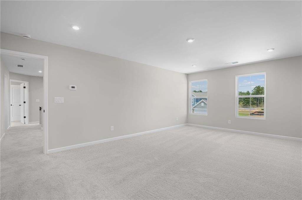 Recessed ceiling lighting, two windows with white trim, light gray wall finishes, light gray carpeting, and a white door frame