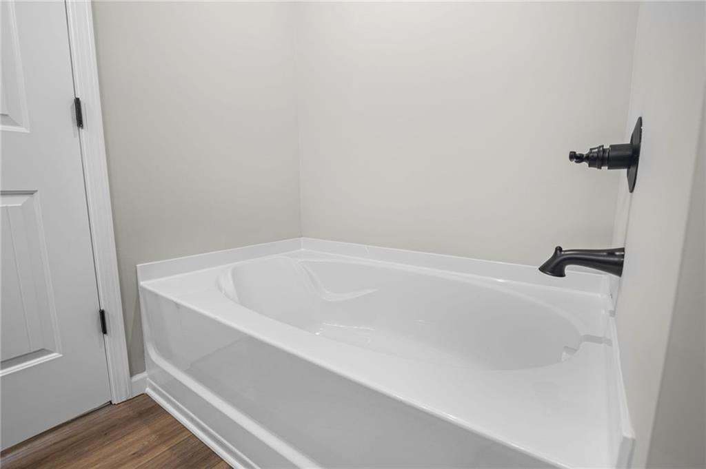 White bathtub with dark bronze fixtures and wood-finish flooring