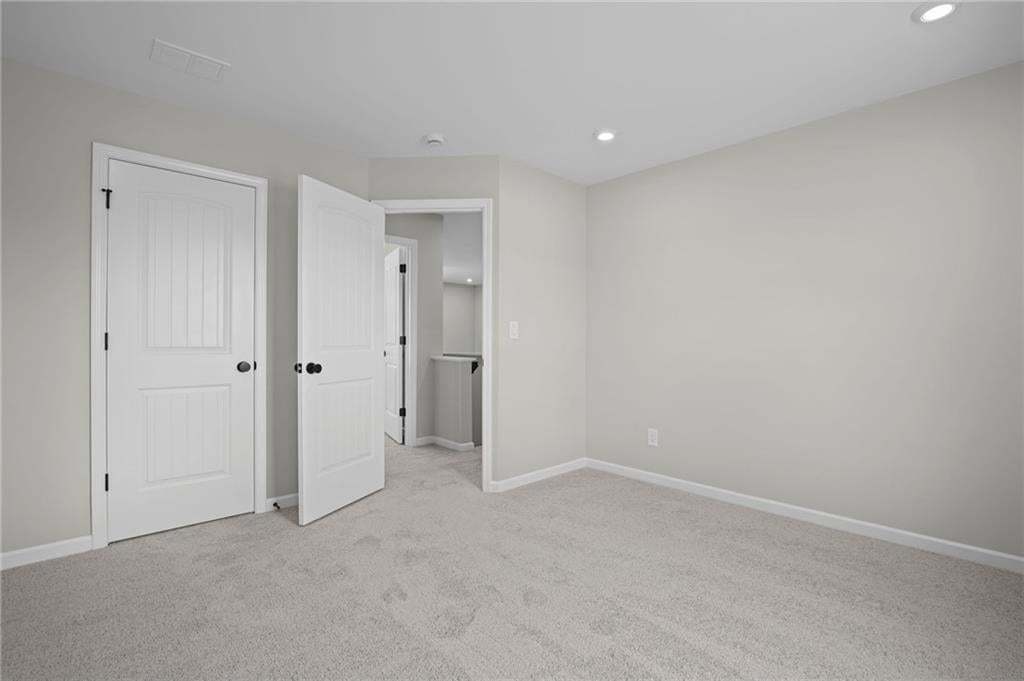 Recessed ceiling lighting, light gray wall paint, and gray carpet flooring