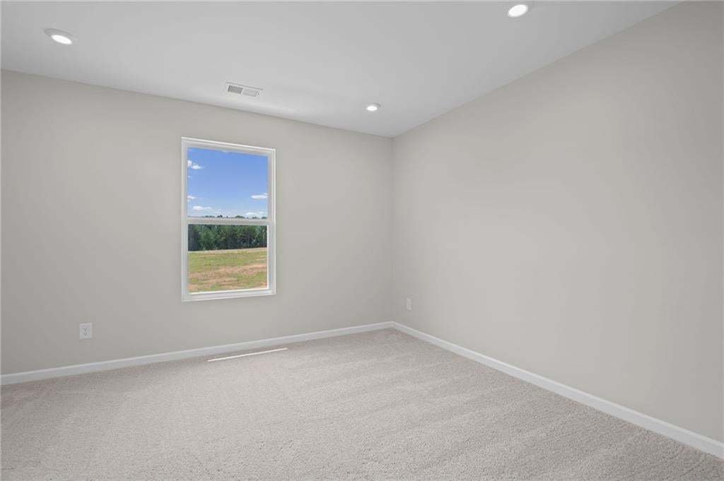 Recessed lighting, light-toned walls, and neutral carpeting