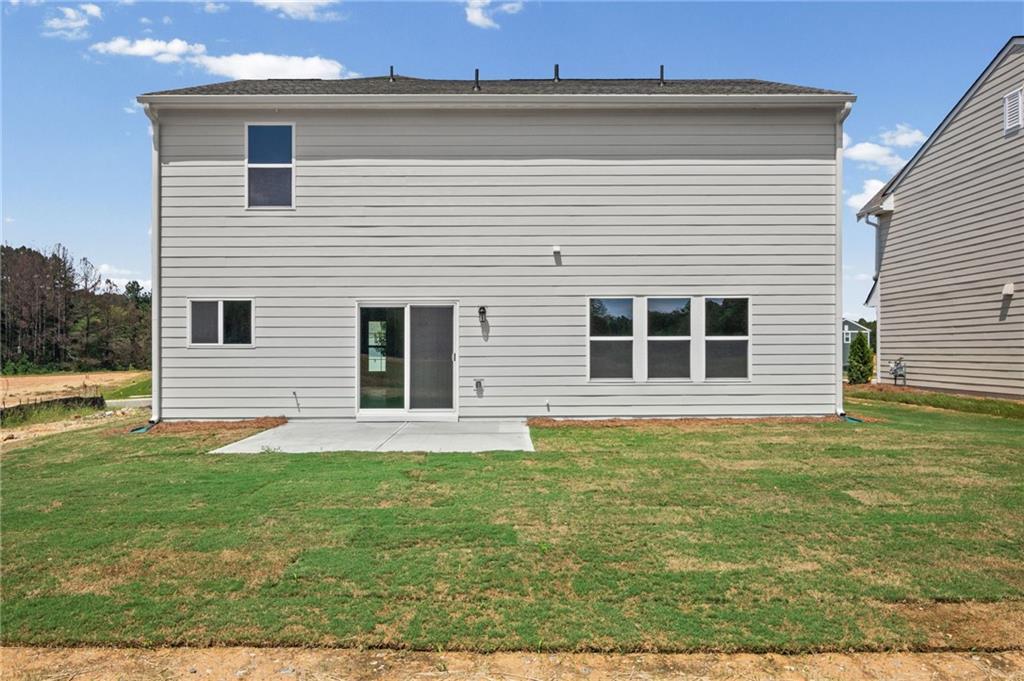Rear exterior with light-colored horizontal siding, a concrete patio, and a sliding glass door