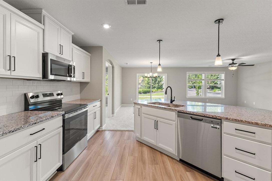 This kitchen boasts pristine white cabinetry, ligh