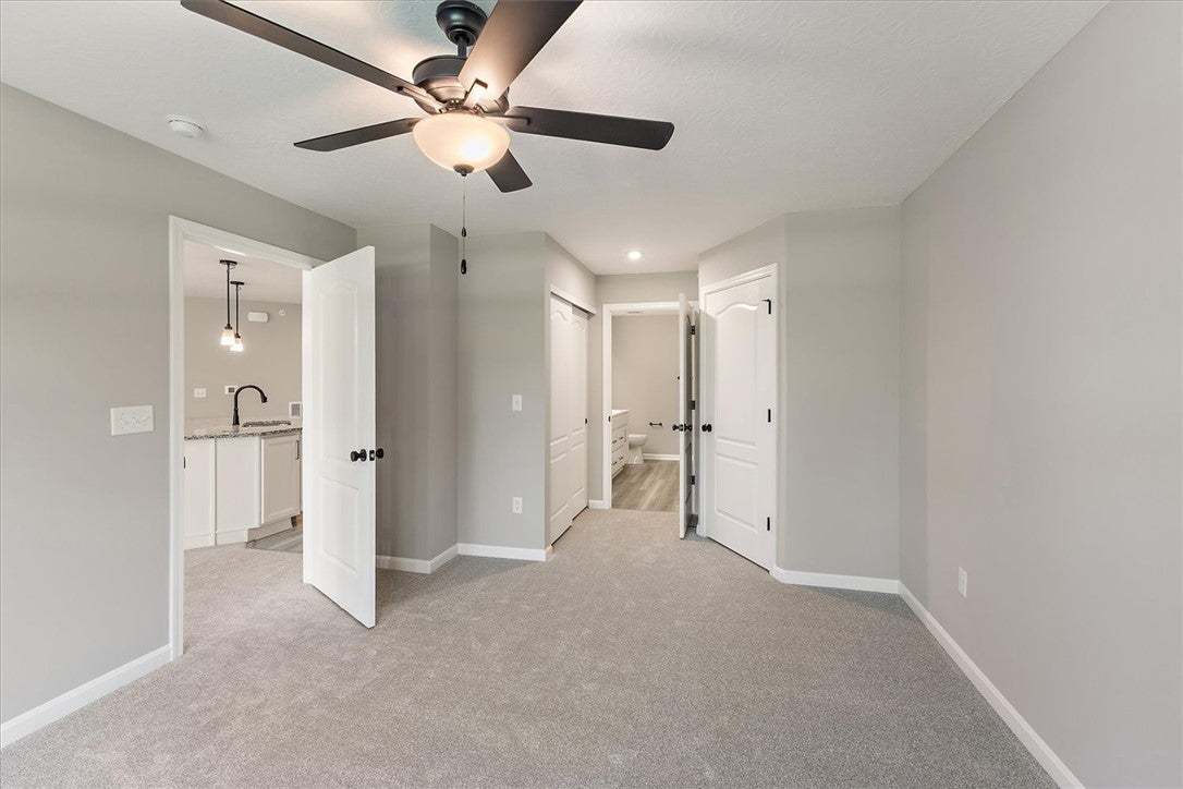 A spacious room features a ceiling fan, soft gray