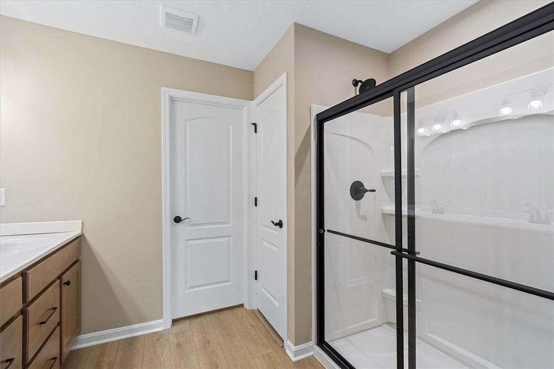 This primary bathroom showcases a glass-enclosed s