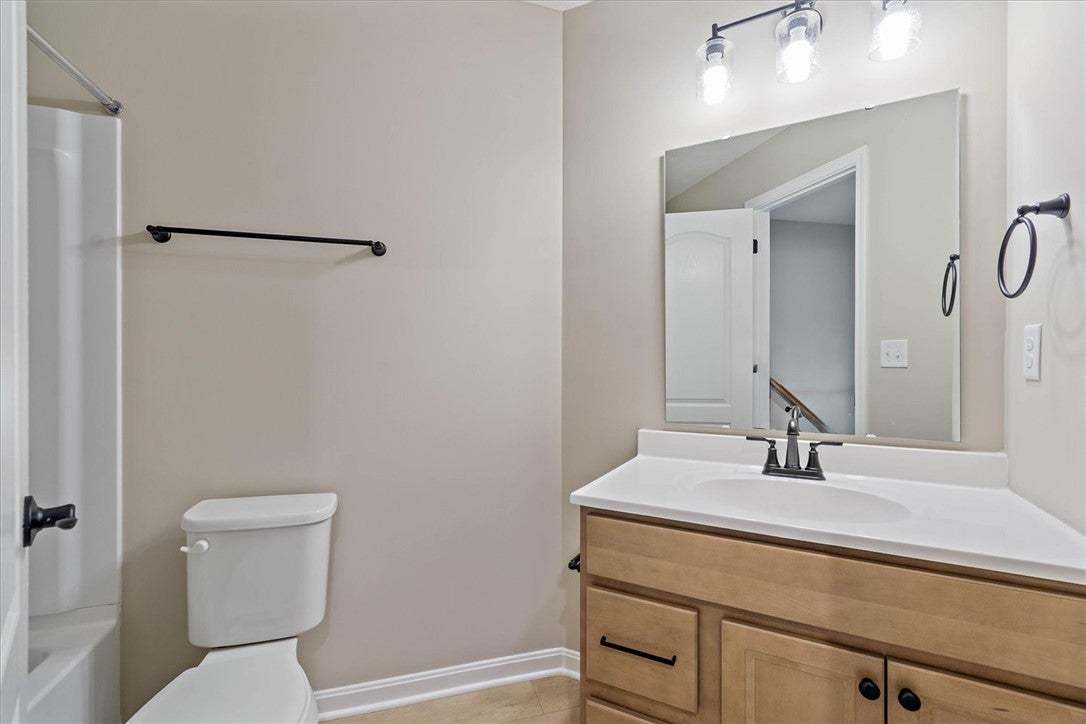 This bathroom features a light wood vanity with a