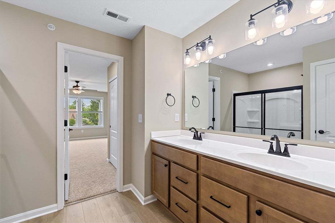 This primary bathroom features a dual vanity, ligh