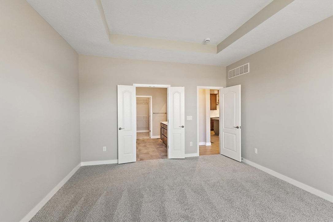 This spacious primary bedroom features soft carpet