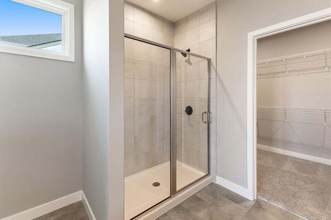 A well-appointed primary bathroom showcases a glas