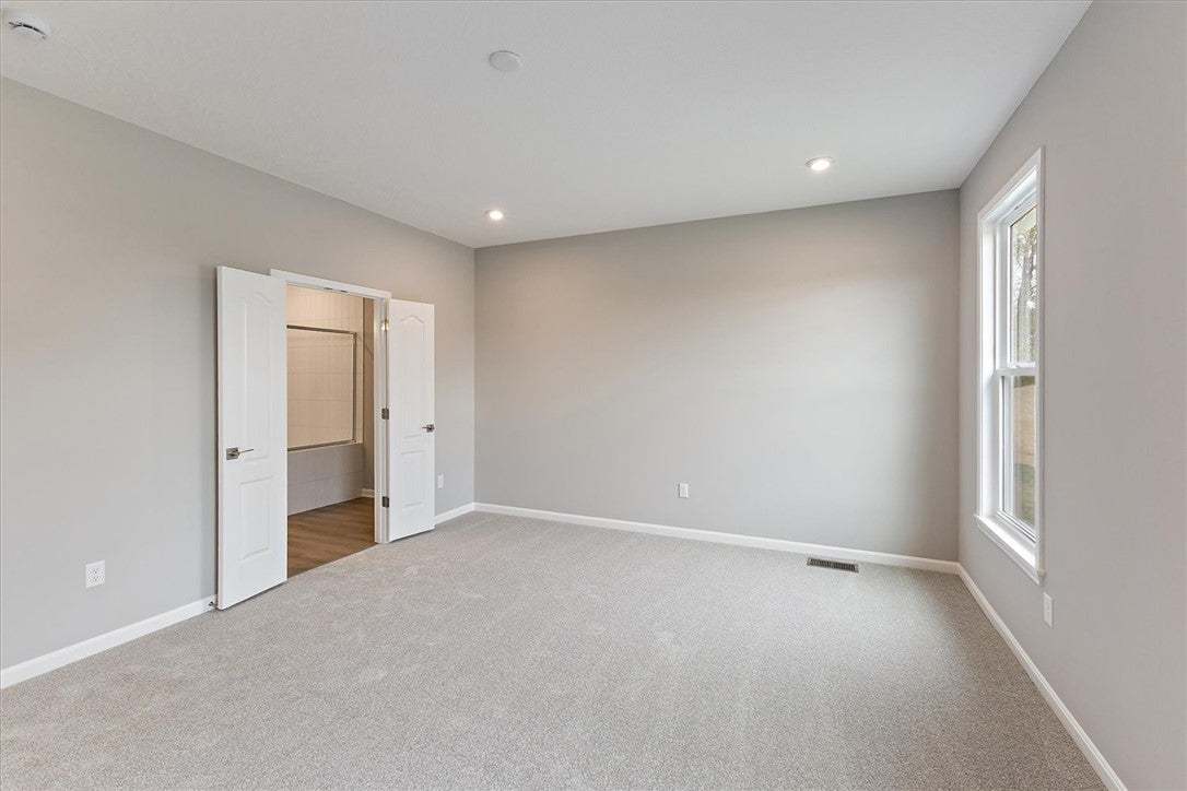 An inviting room boasts soft carpeting, recessed l