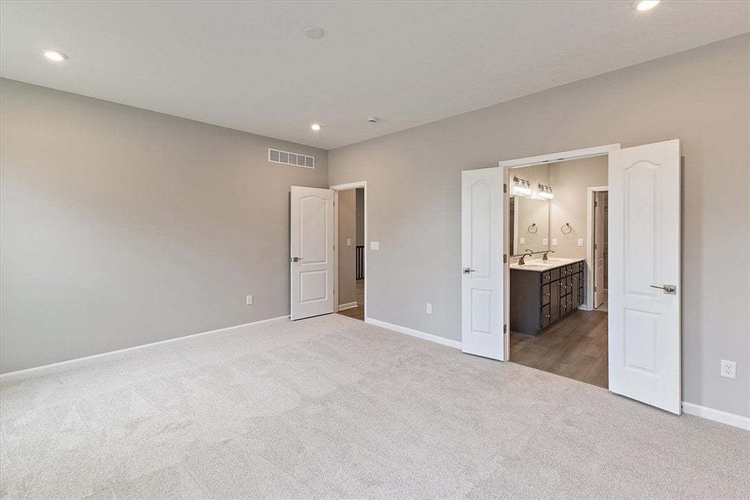 This spacious primary bedroom features soft carpet