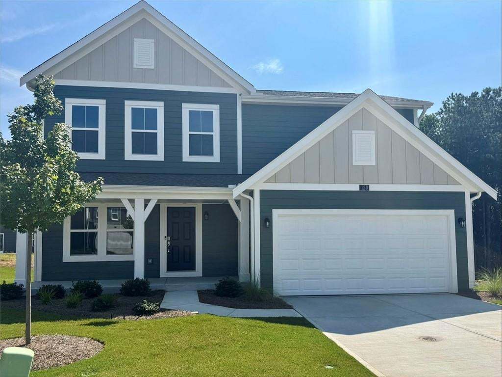 View of front of home with board and batten siding, covered porch, concrete driveway, and a front lawn