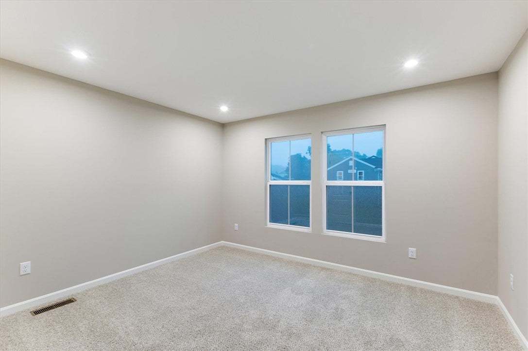 A spacious bedroom features plush carpeting, reces