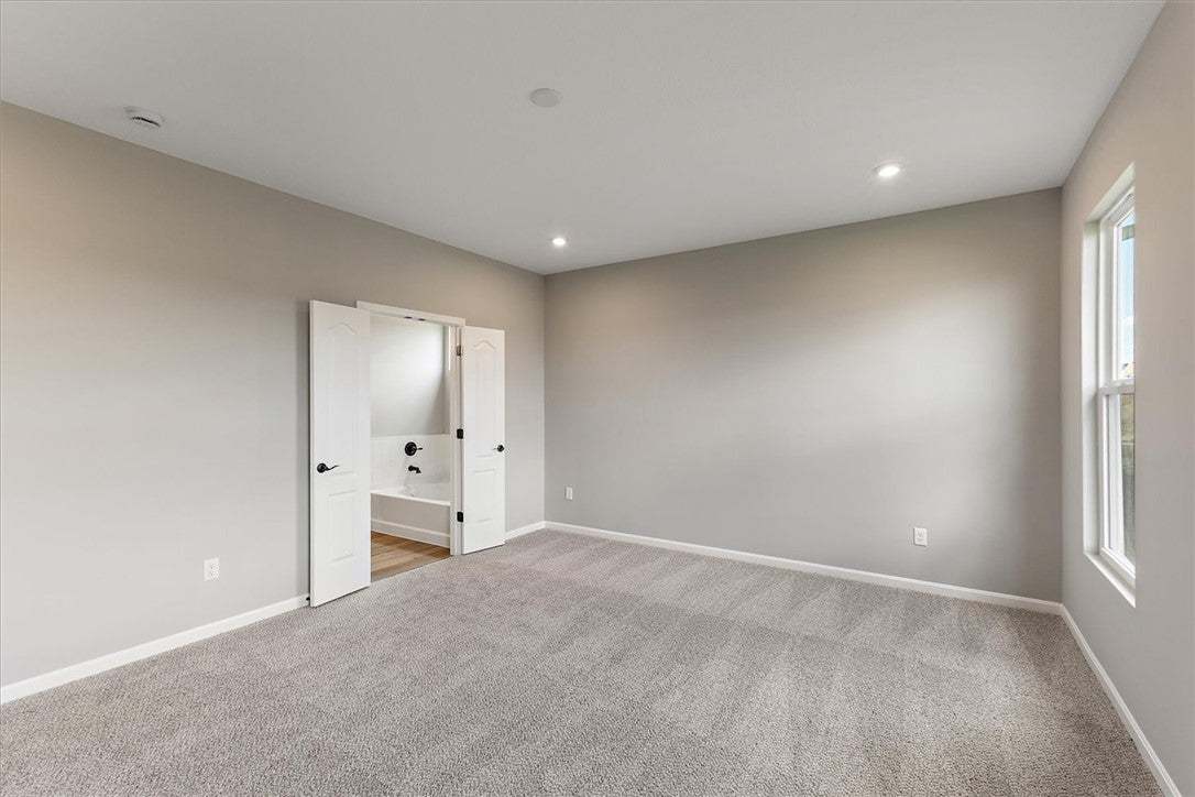 A spacious primary bedroom featuring plush carpeti