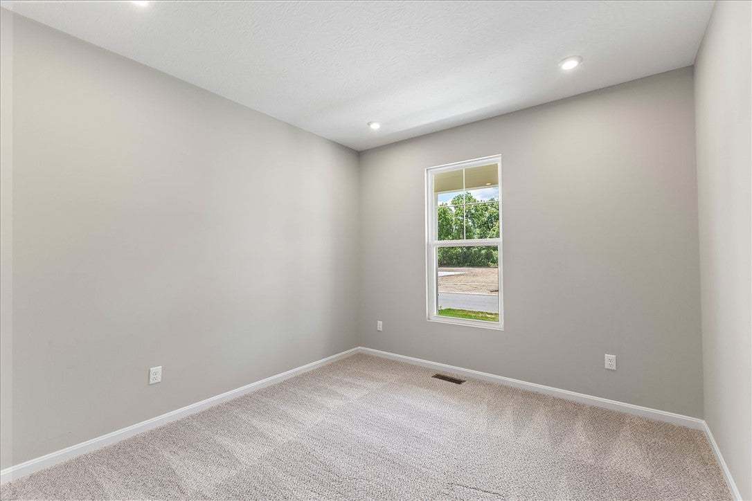 A well-lit bedroom features plush carpeting and a