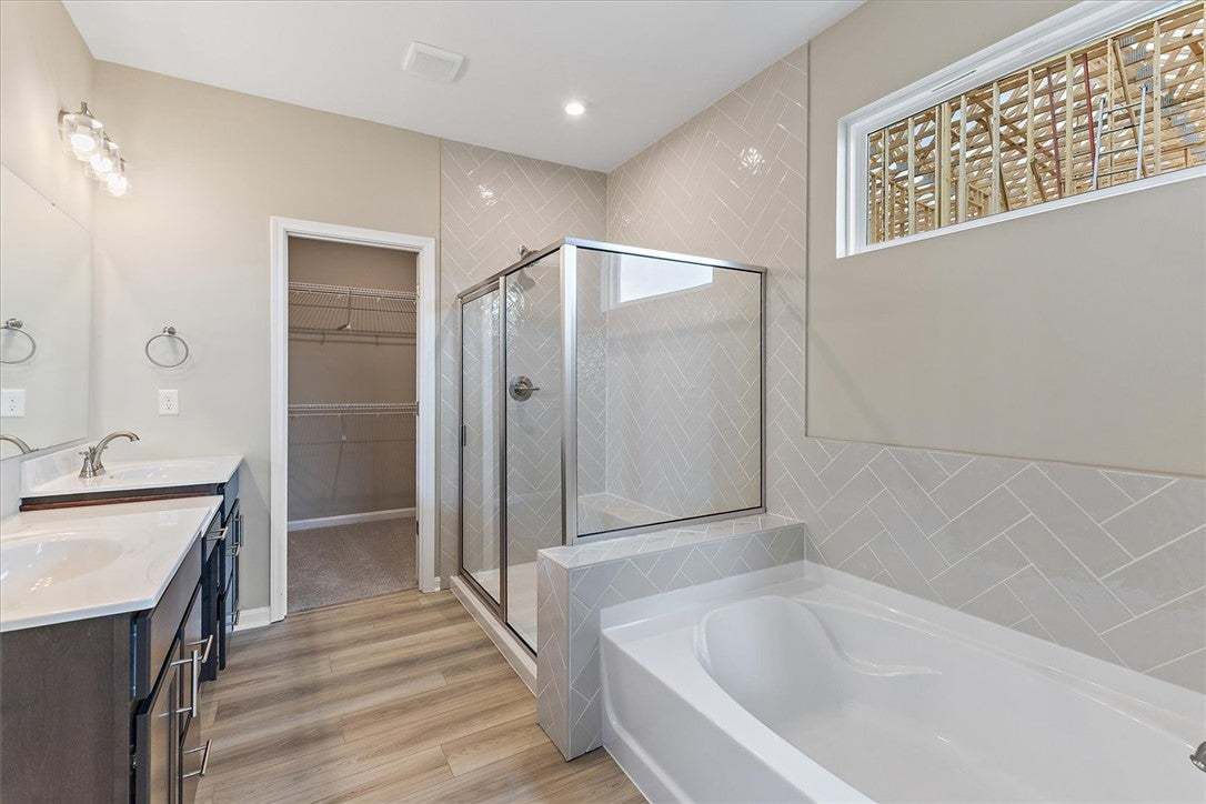 This spacious bathroom offers dual vanities, a sep