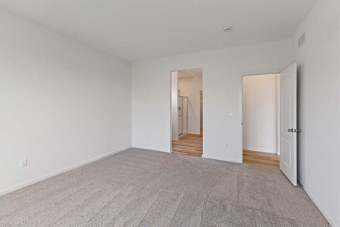A spacious bedroom features soft gray carpeting an