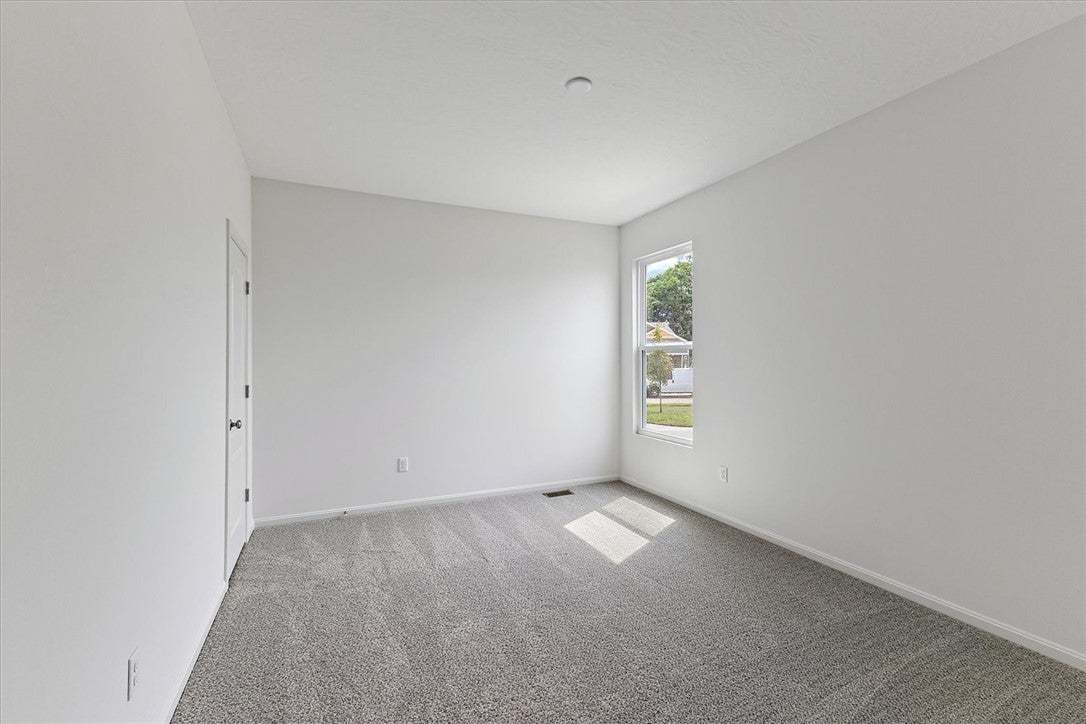 A well-lit bedroom features plush carpeting and a