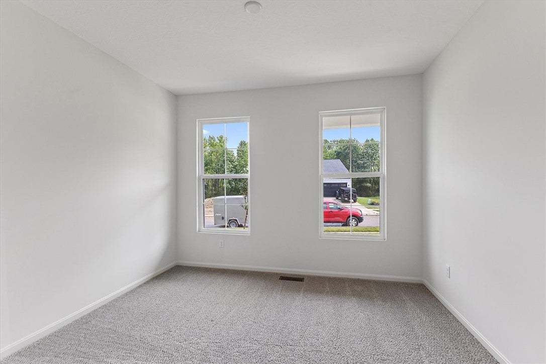 A well-lit bedroom features plush carpeting and mu