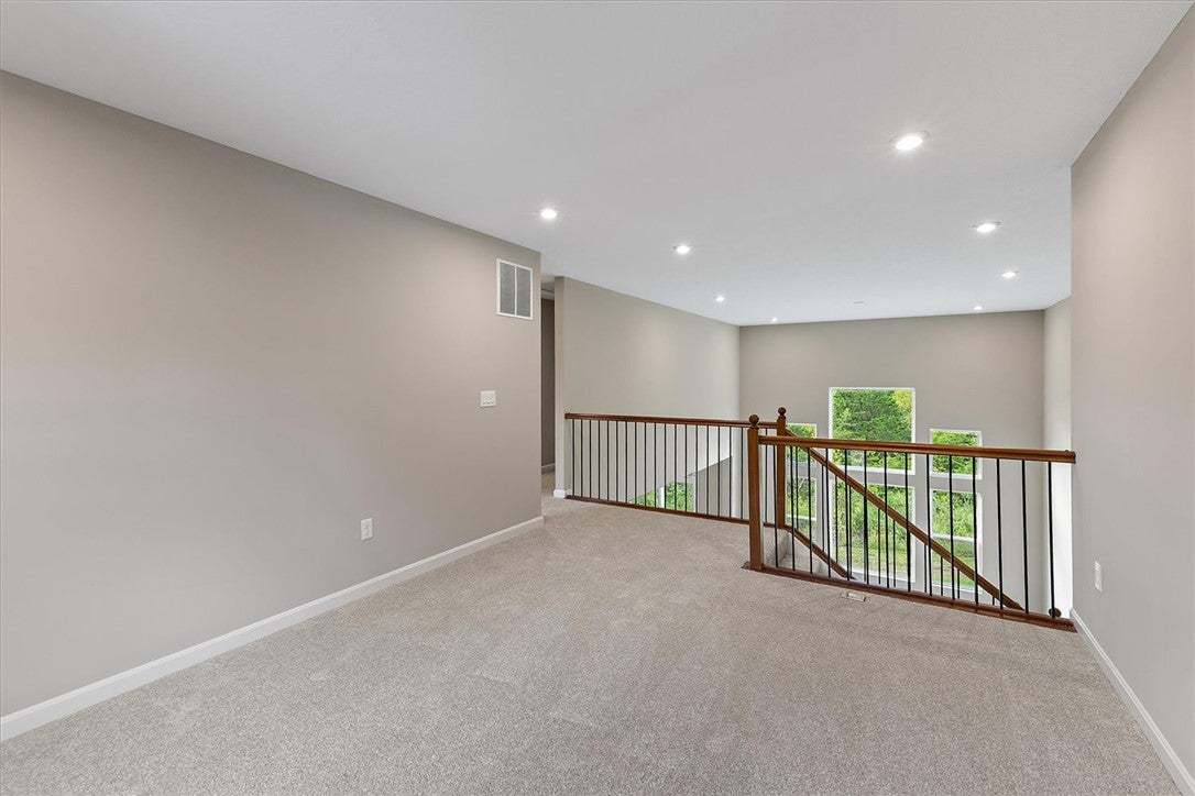An airy upper-level landing features plush carpeti