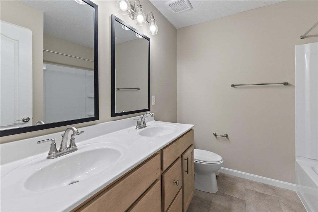 Double vanity sinks stand alongside neutral tile f