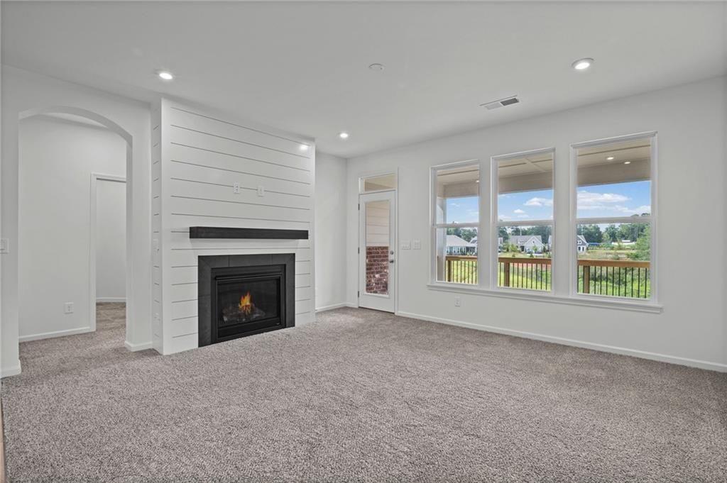 Living area with a shiplap fireplace, recessed lighting, and soft carpet flooring