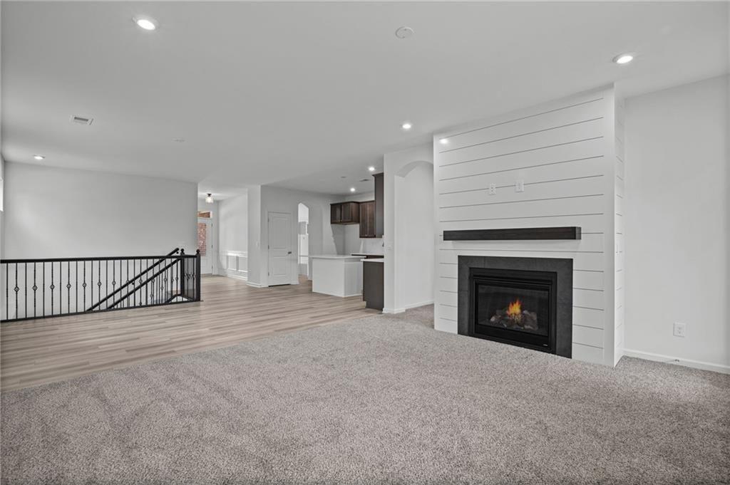 Living area featuring a shiplap-style fireplace with a dark mantel, a gas insert, and recessed lighting