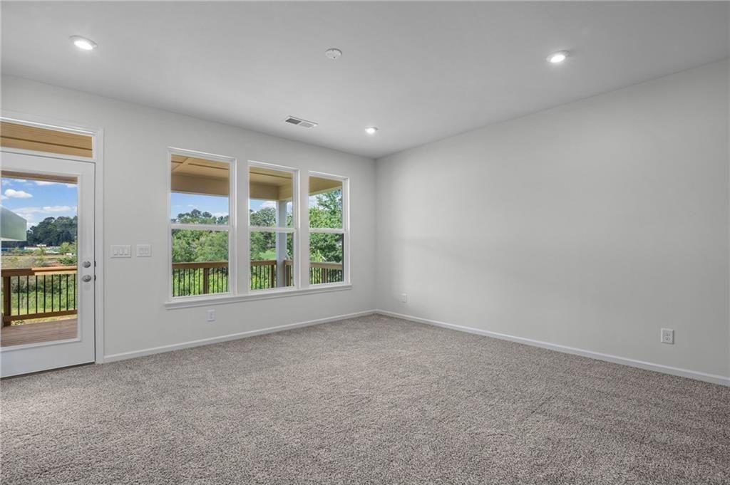Carpeted room with recessed lighting and a sliding glass door opening to a wooden deck