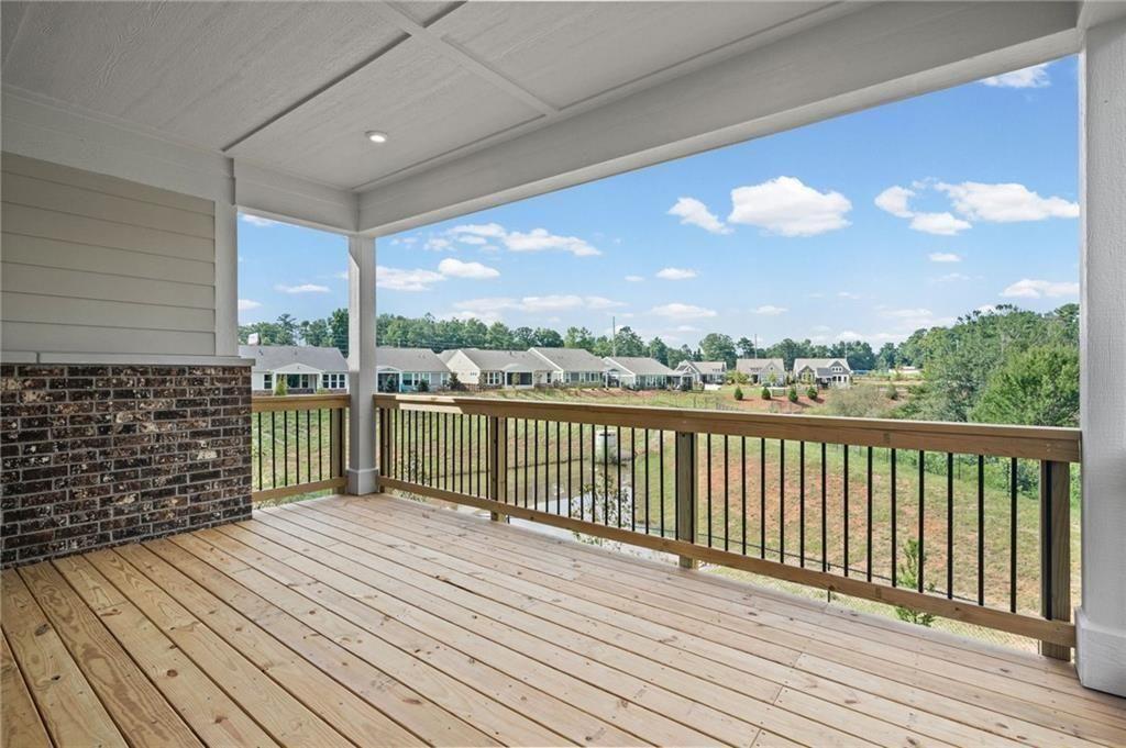 Spacious covered porch with natural wood flooring and a classic brick accent wall