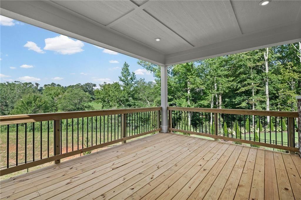 Expansive covered deck featuring wood plank flooring, a wood railing with black balusters, and recessed ceiling lighting