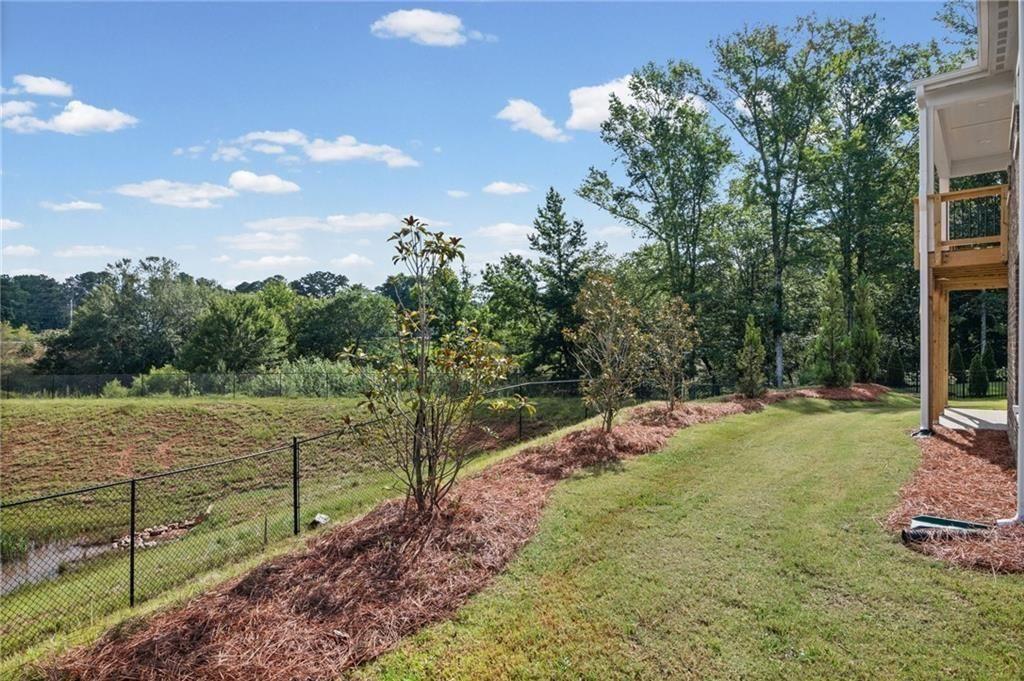 Expansive green lawn with a sloped landscape and mature trees