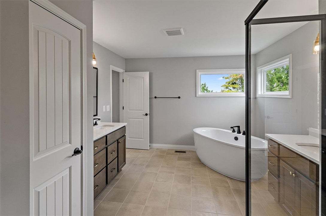 An elegant freestanding soaking tub anchors this w