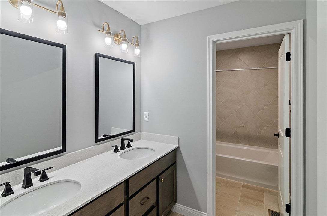 A modern double vanity stands adjacent to a tiled