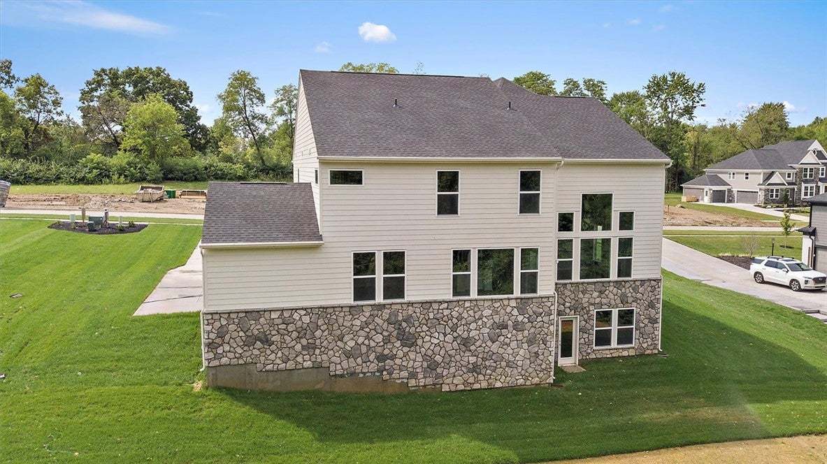 A stone-and-siding exterior rises above a manicure