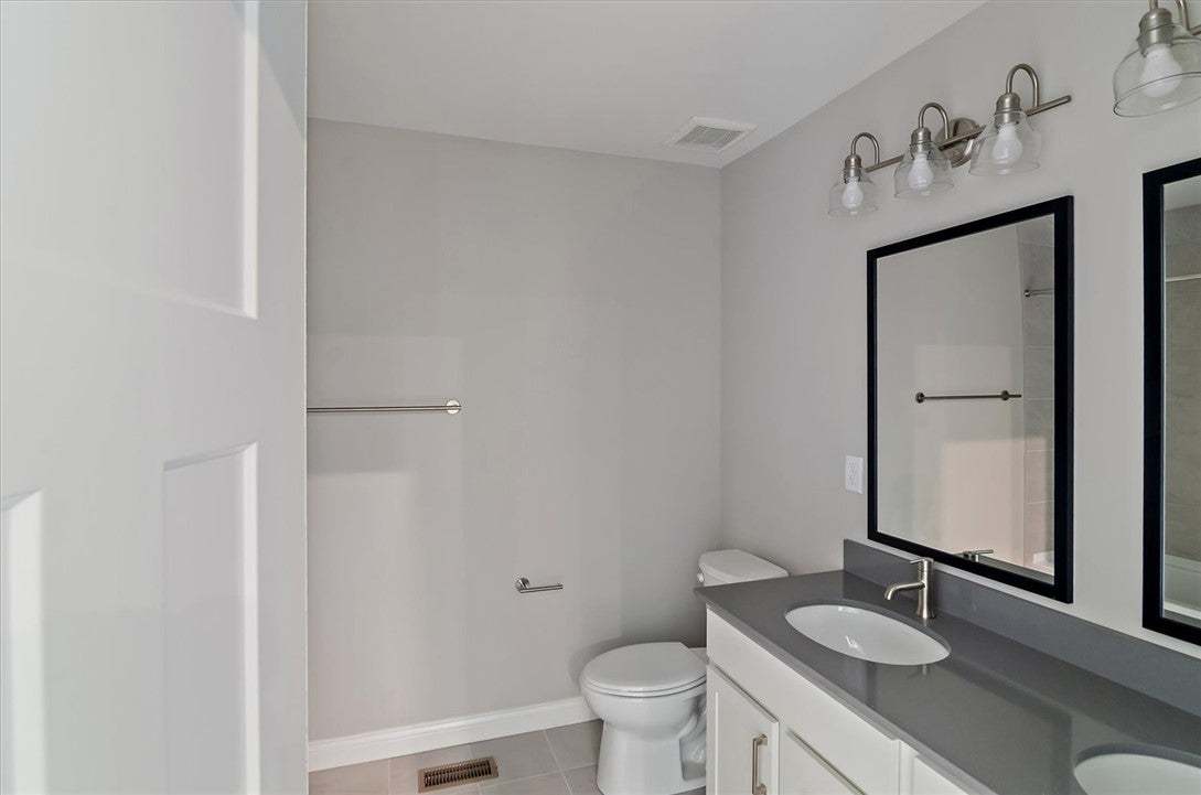 A modern double vanity features sleek stone counte