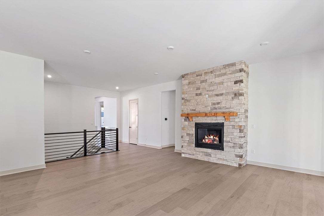 Warm wood flooring and a floor-to-ceiling stone fi