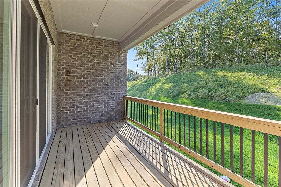 A covered wooden deck features brick accents and p