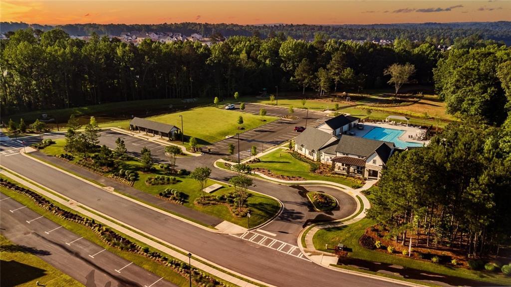Community amenity center featuring a swimming pool, clubhouse, and expansive green spaces