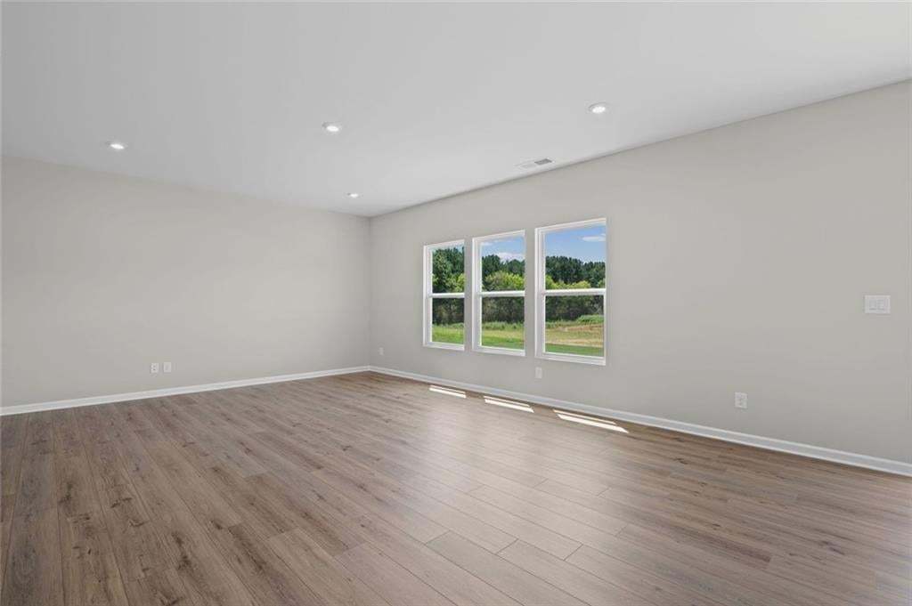 Recessed ceiling lighting, wood-finish flooring, white trim, and multiple windows