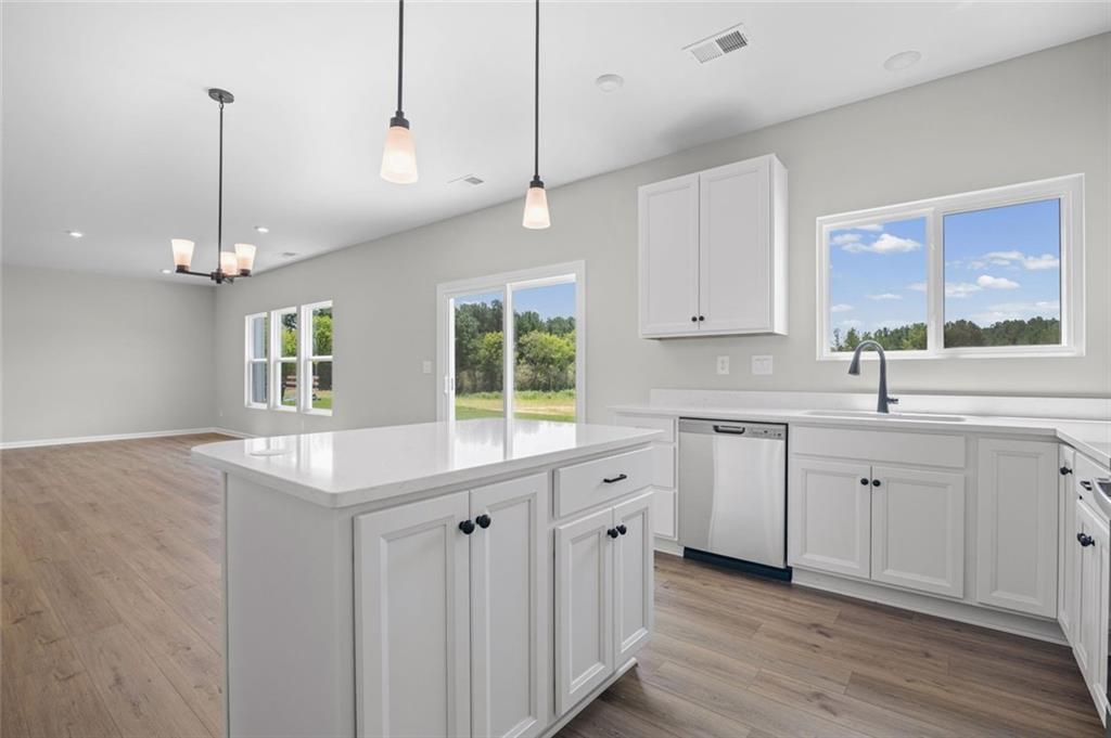 Open-concept living space with wood-finish flooring, a kitchen island, white cabinetry, and stainless steel appliances