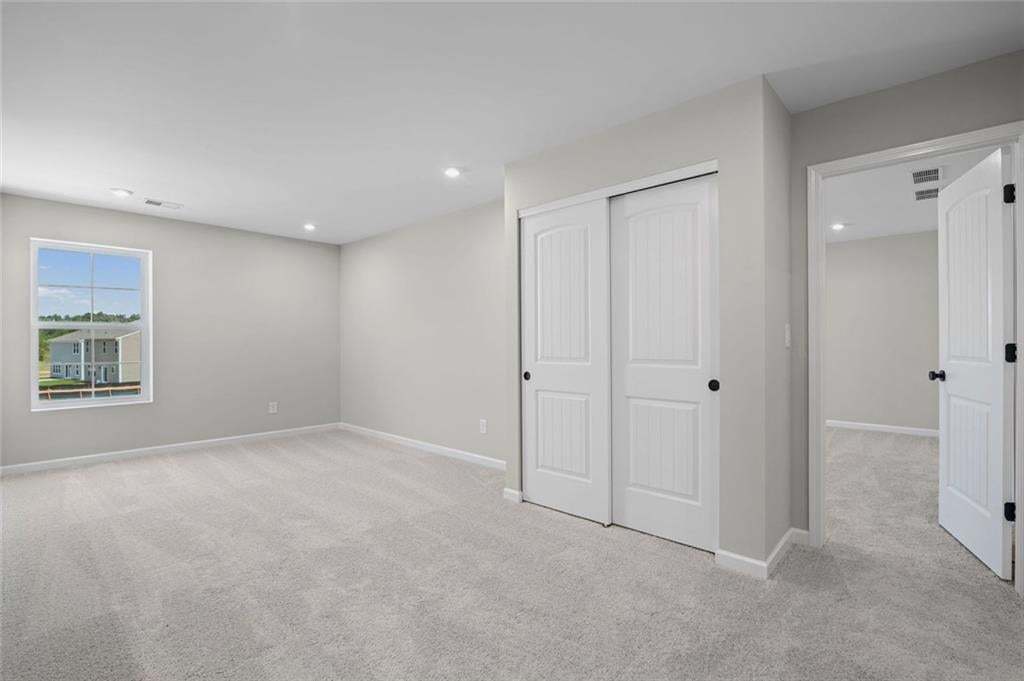 Expansive carpeted room featuring a window, recessed lighting, and a bi-fold closet with panel doors