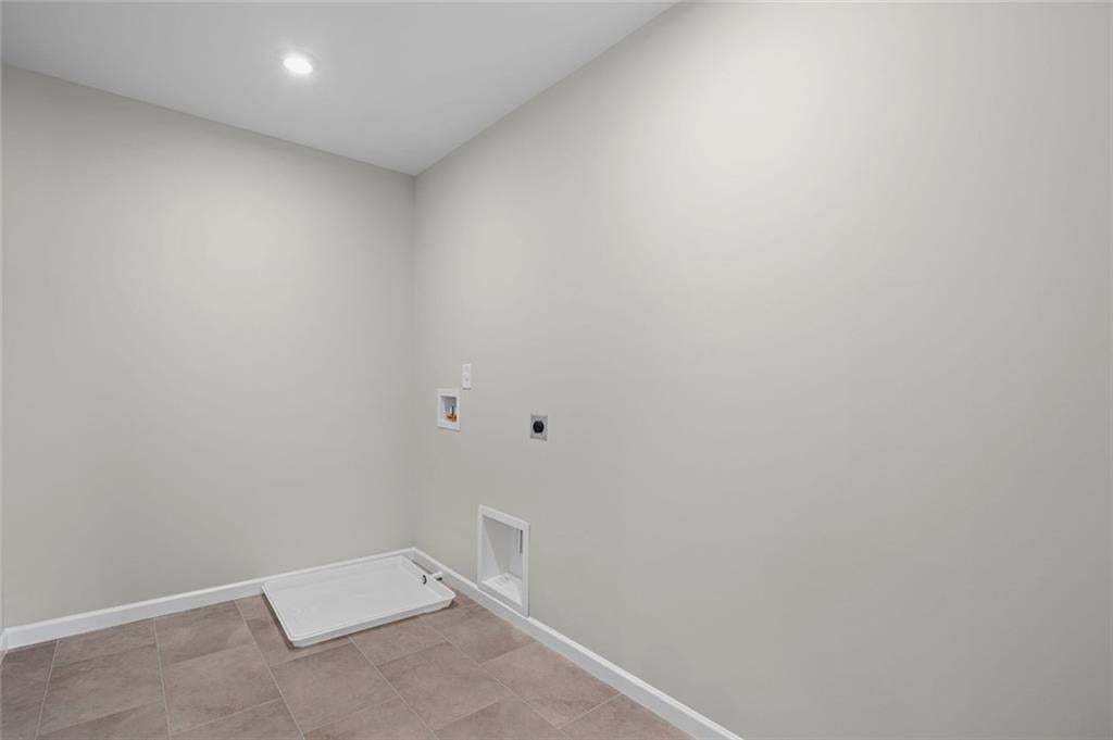 Recessed ceiling light, white painted walls, tile flooring, and utility hookups