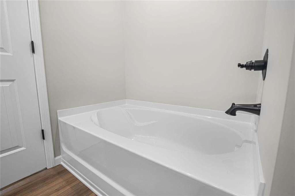 White bathtub with dark bronze fixtures and wood-finish flooring