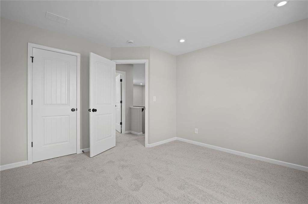 Recessed ceiling lighting, light gray wall paint, and gray carpet flooring