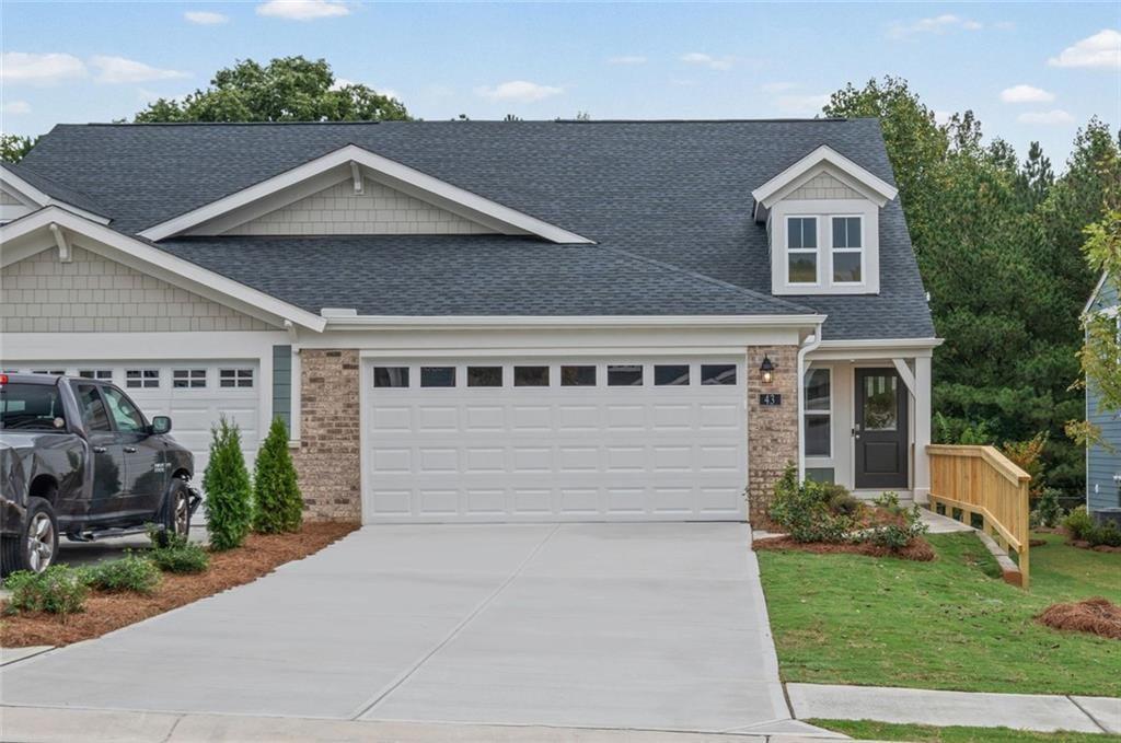 View of front of house with an attached garage, a front lawn, driveway, and brick siding