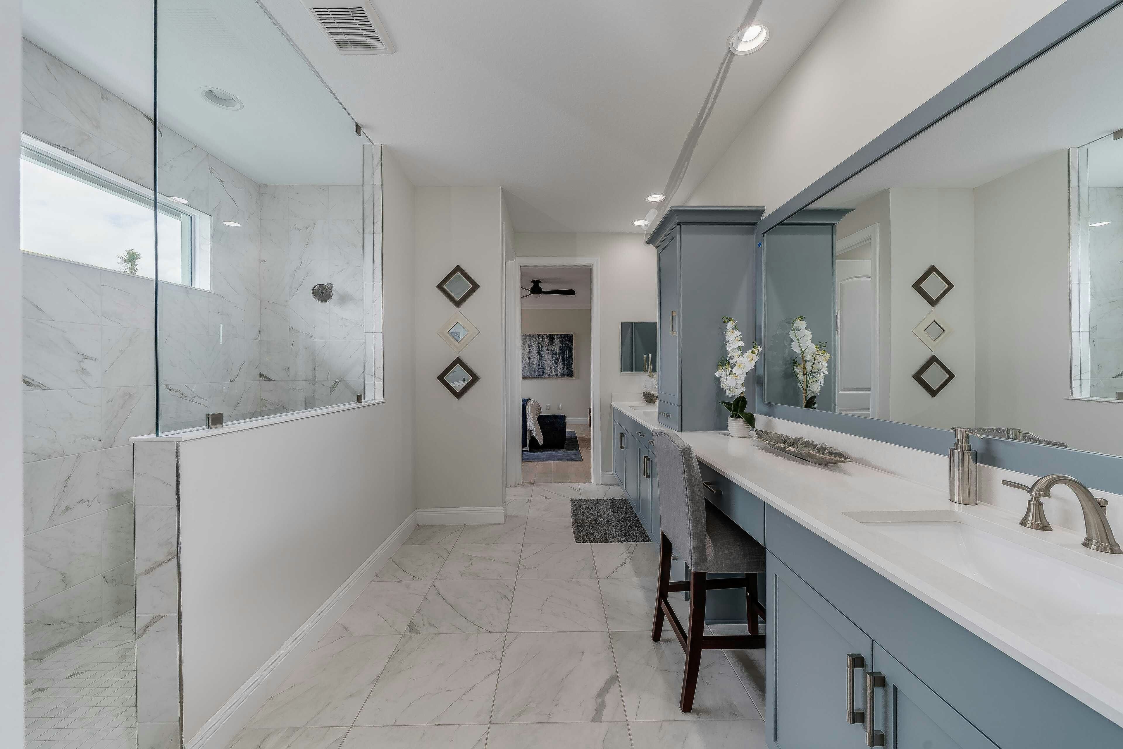 Master bath split vanity with view of walk-in shower and large tile flooring