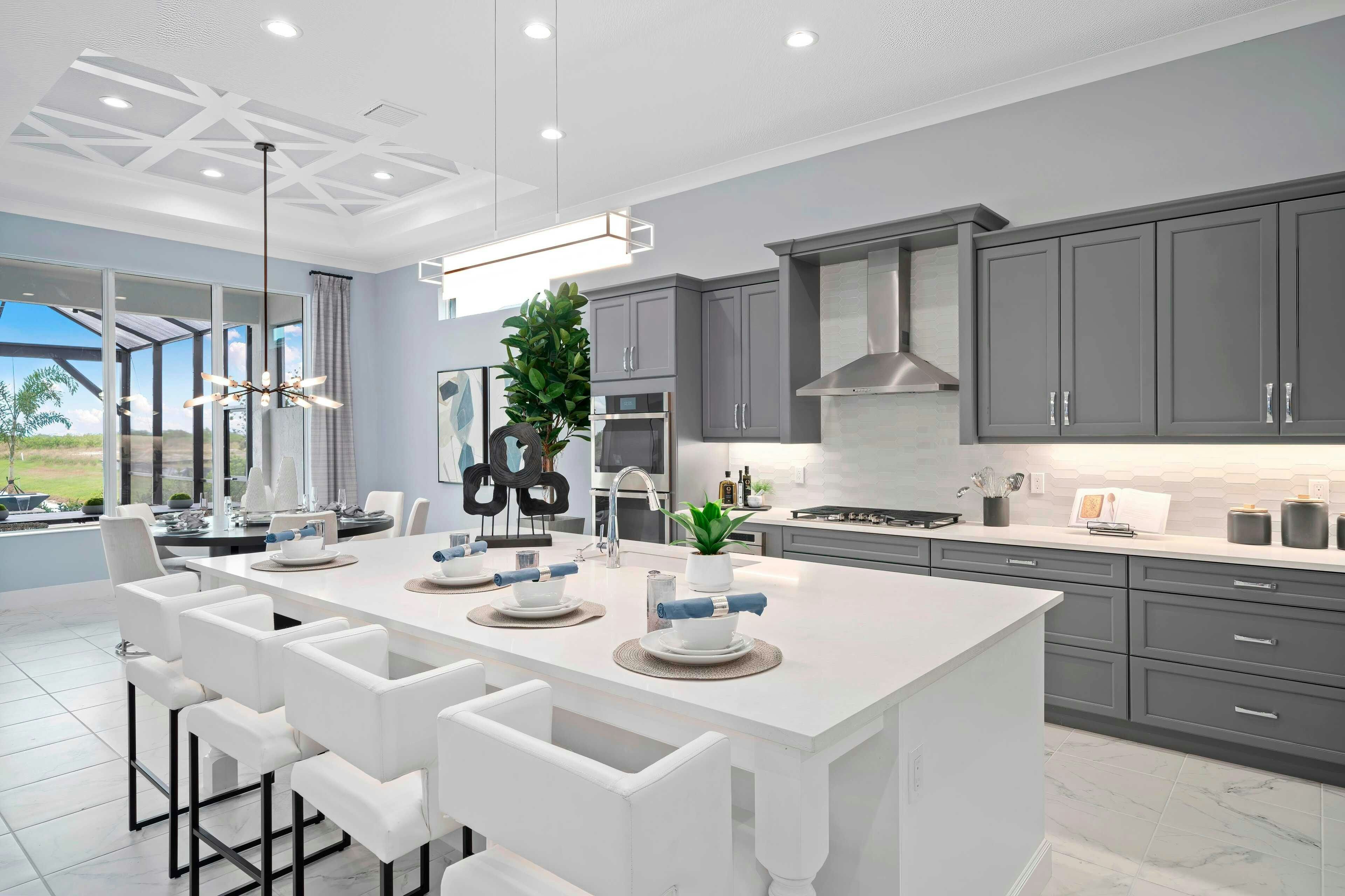 Kitchen with white island and quarts, grey cabinets and stainless appliances