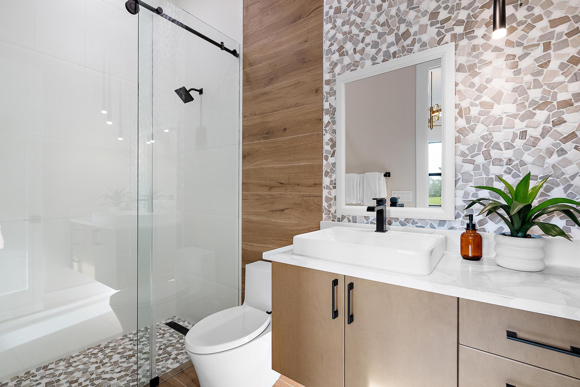 Secondary bath with pebble tile on floor and wall, black accents