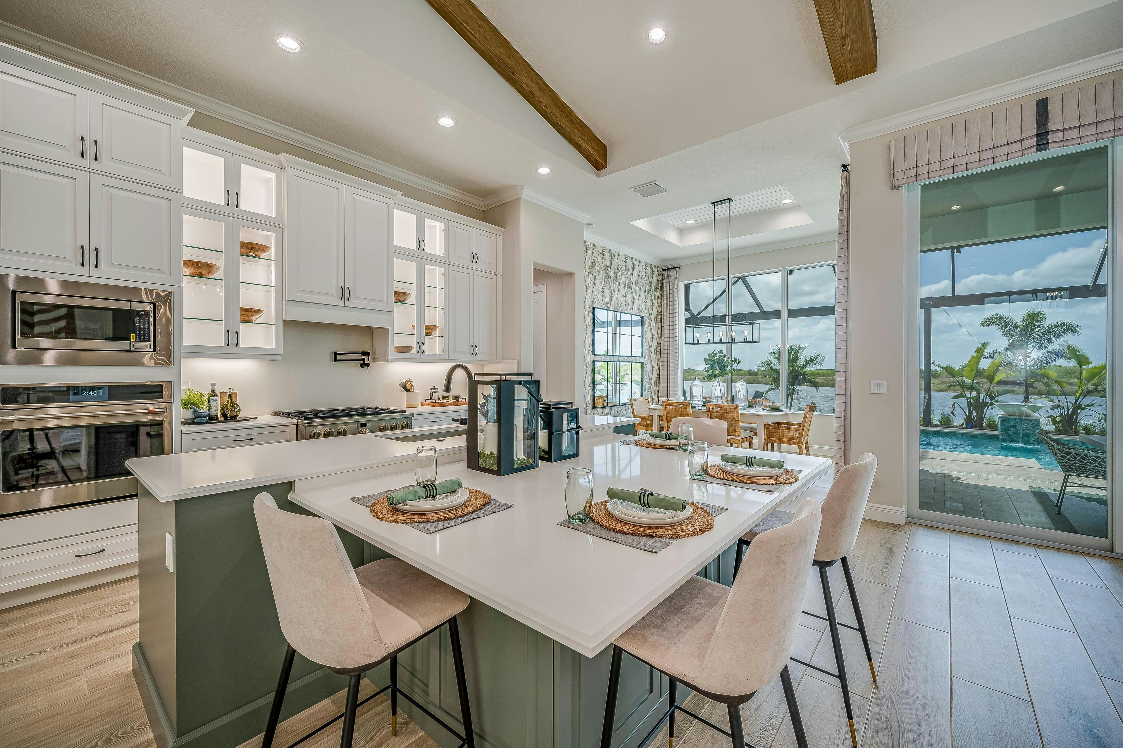 Expansive island with green cabinets and lowers seating, white wall cabients with glass doors